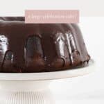 A sour cream chocolate cake on a cake stand, topped with chocolate ganache.