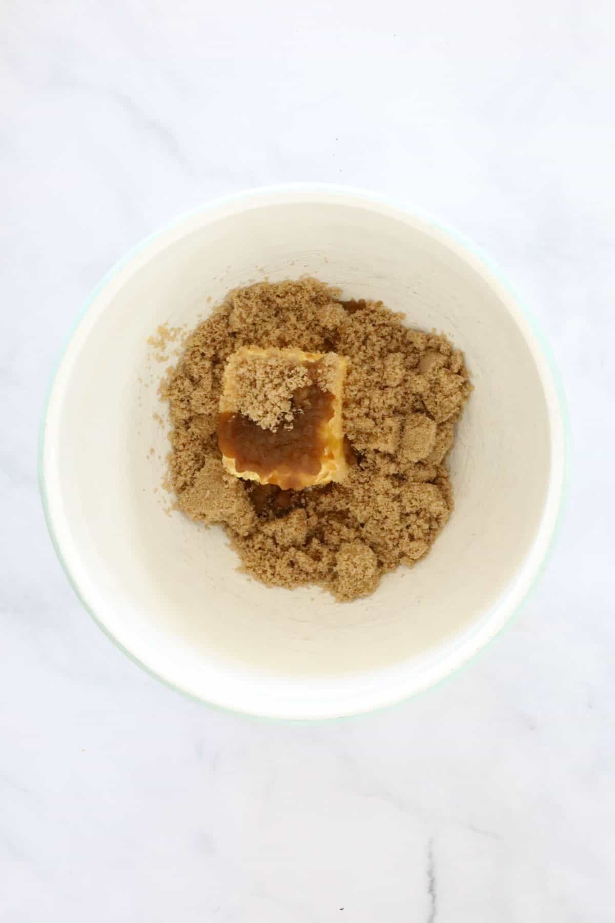Brown sugar and butter in a white mixing bowl.