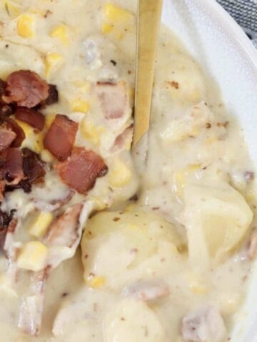 A bowl of Creamy Chicken And Corn Soup with potatoes and bacon.
