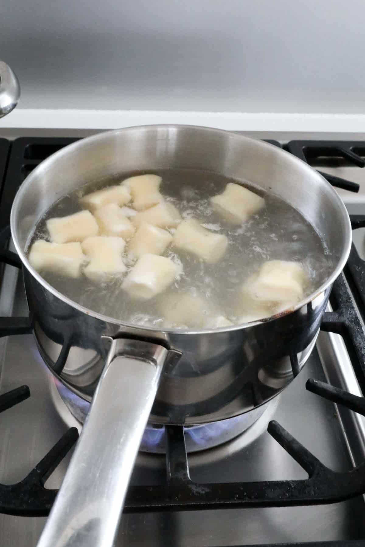 Gnocchi cooking in a pan of boiling water.