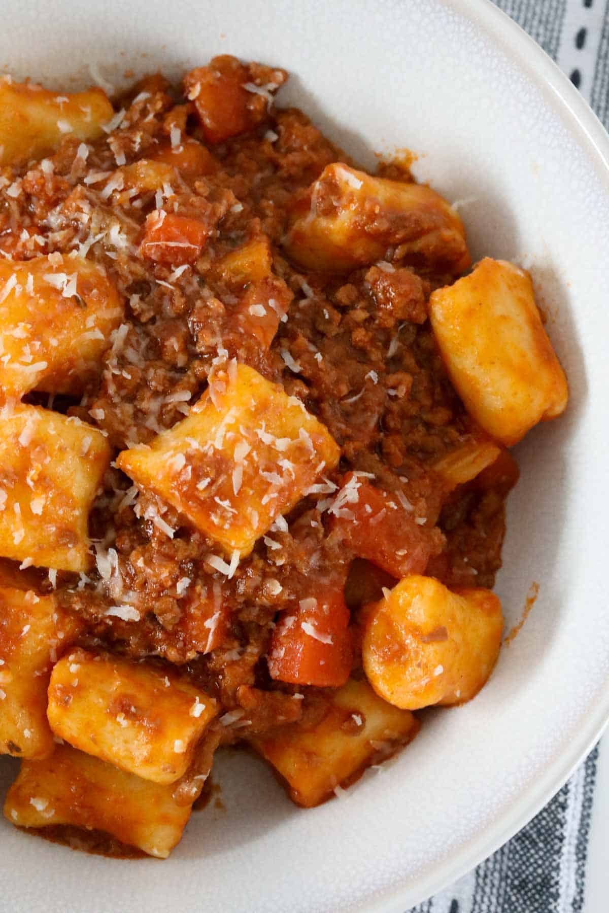A bowl of ricotta gnocchi served with bolognese sauce.