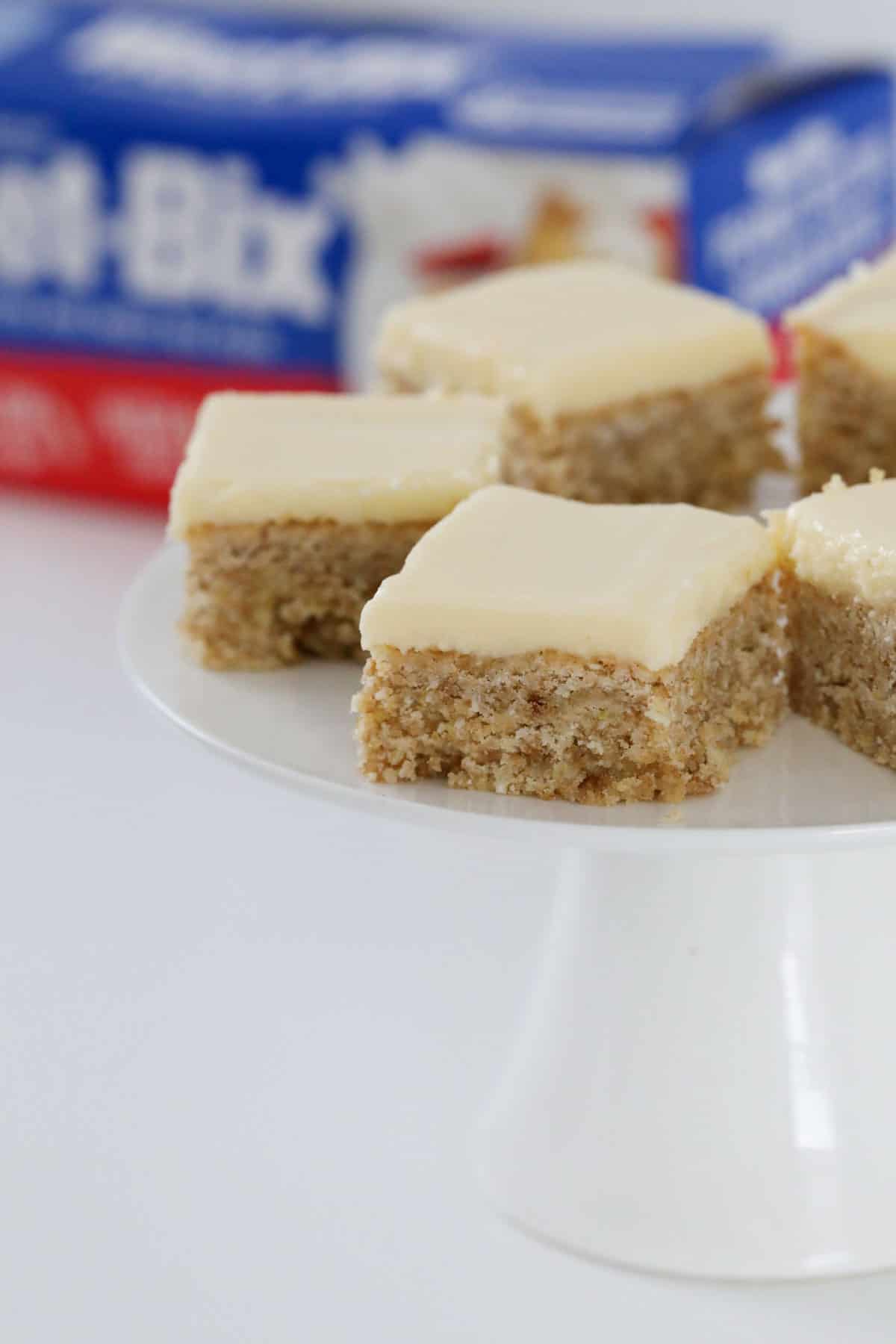 Squares of Weet-Bix slice on a white cake stand.
