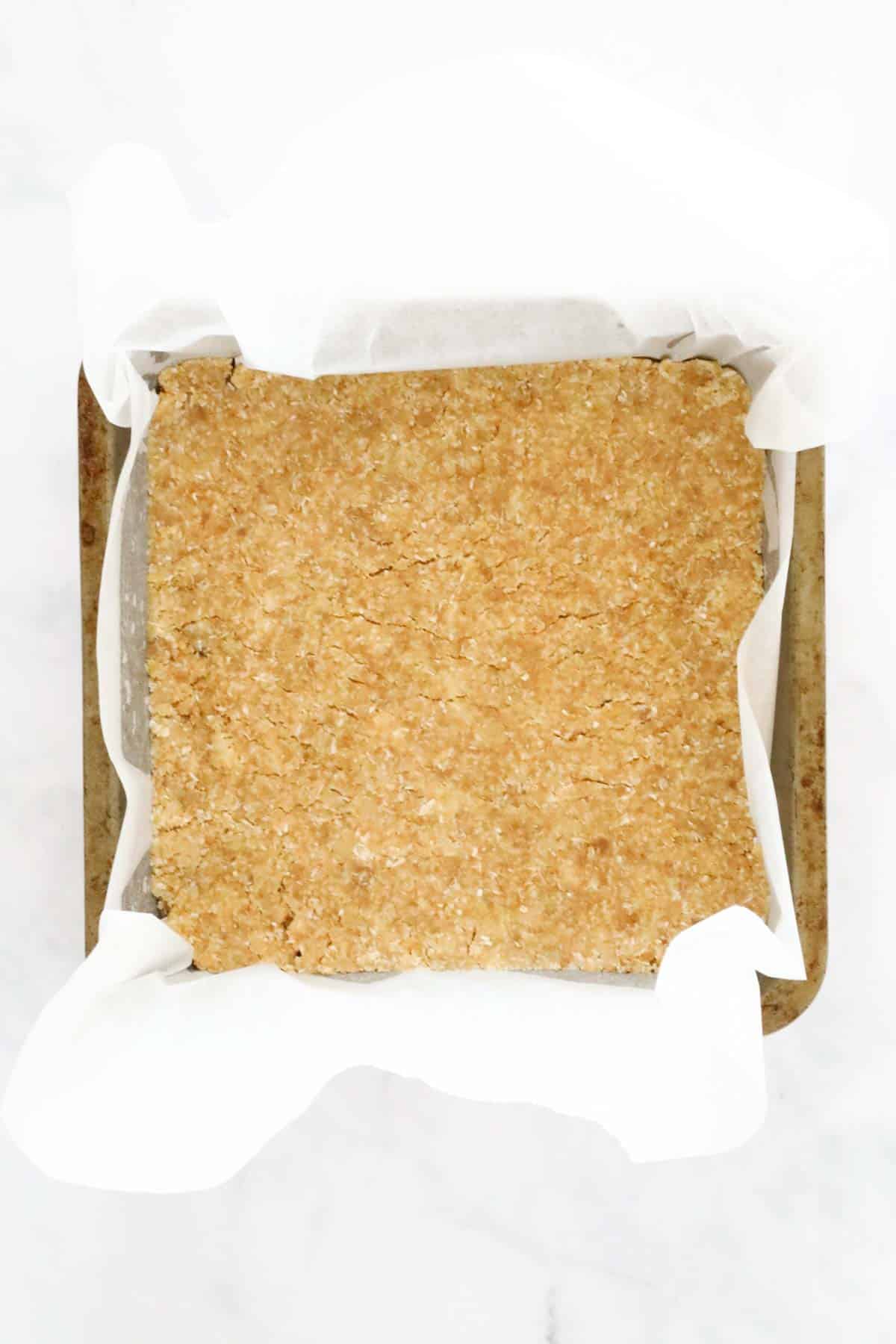 The Weet-Bix slice base pressed into a lined baking tin.