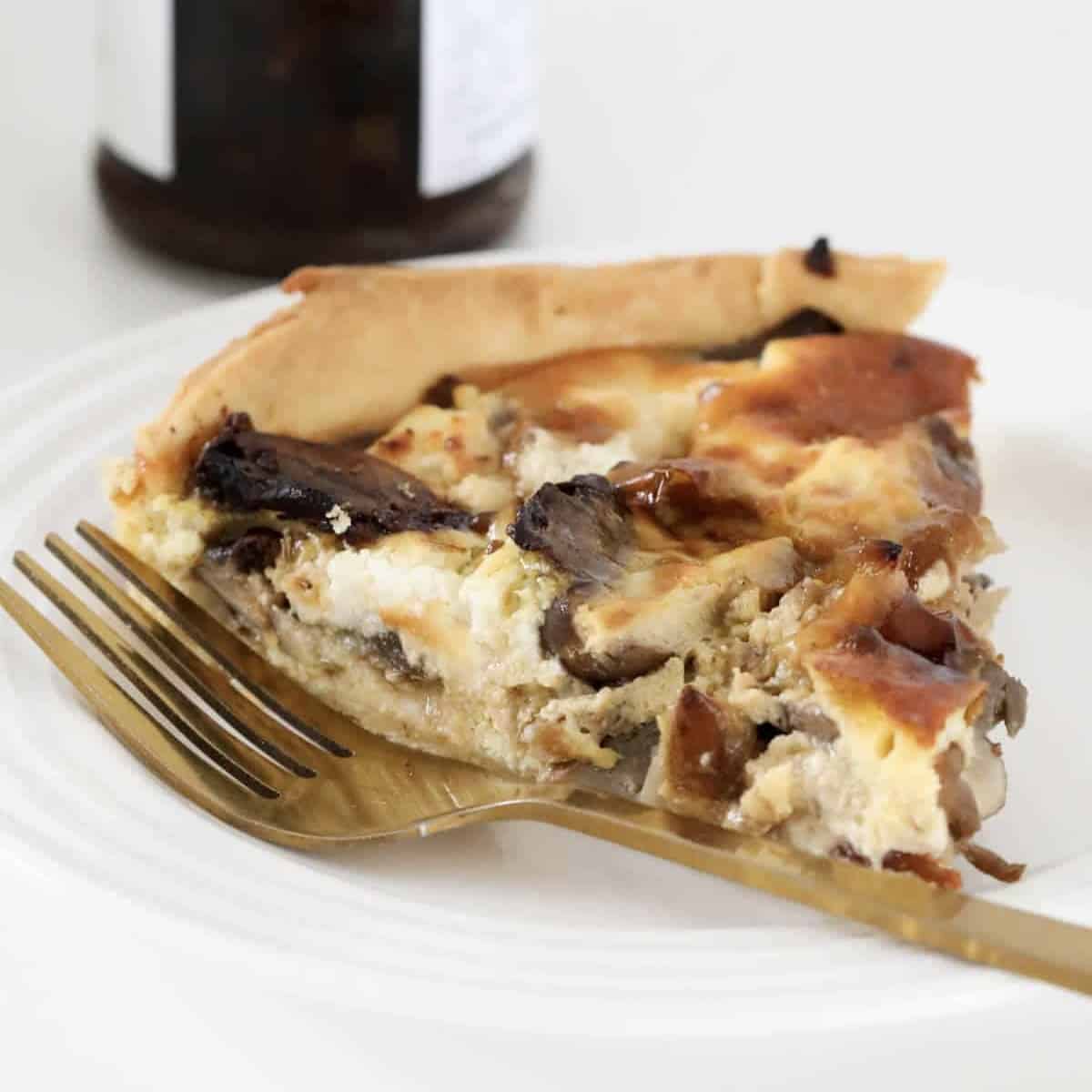 A piece of mushroom savoury tart with feta and caramelised onion.