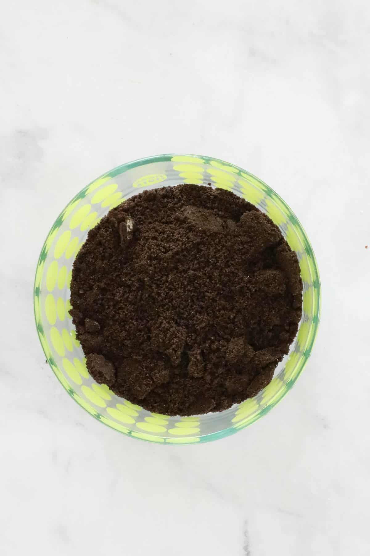 Crushed Oreos in a coloured glass bowl.