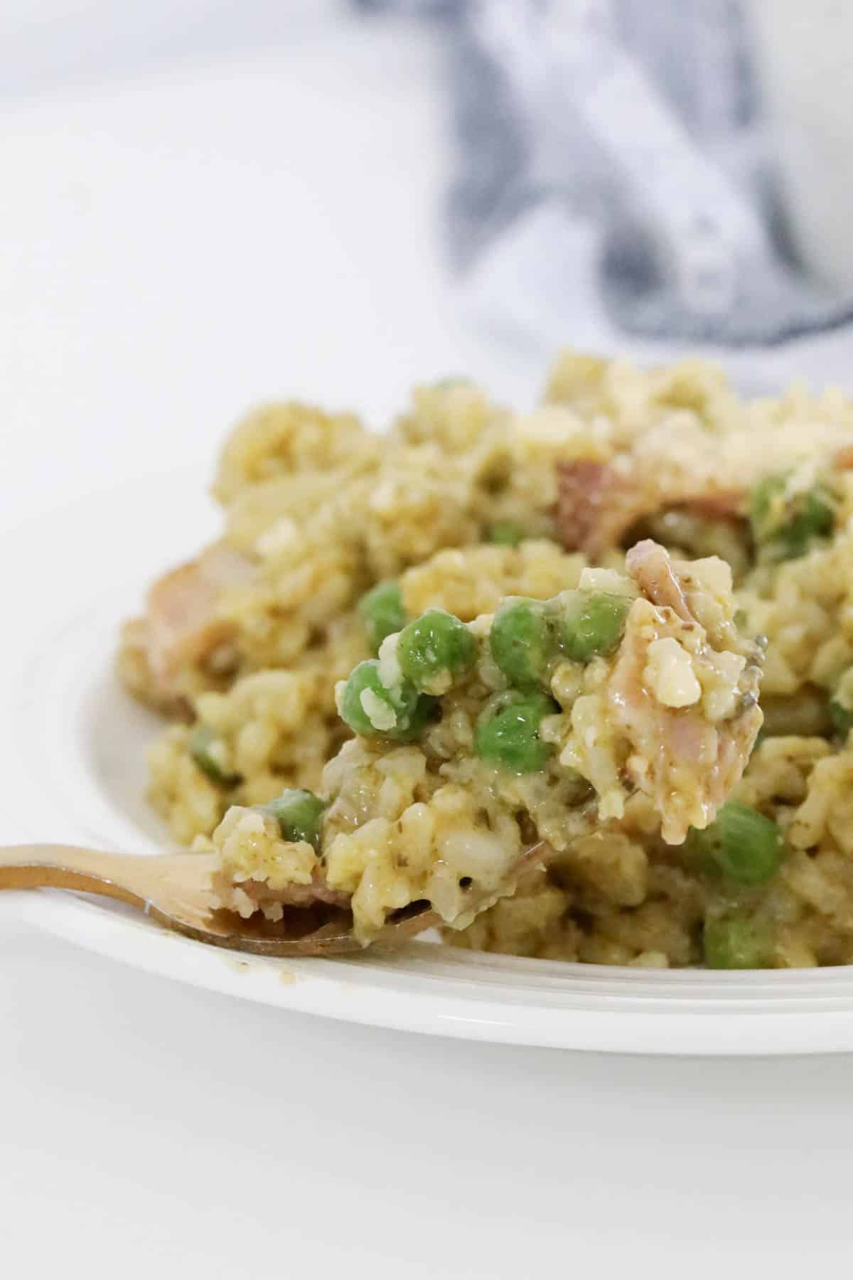 A fork holding up a forkful of the bacon and pea risotto.
