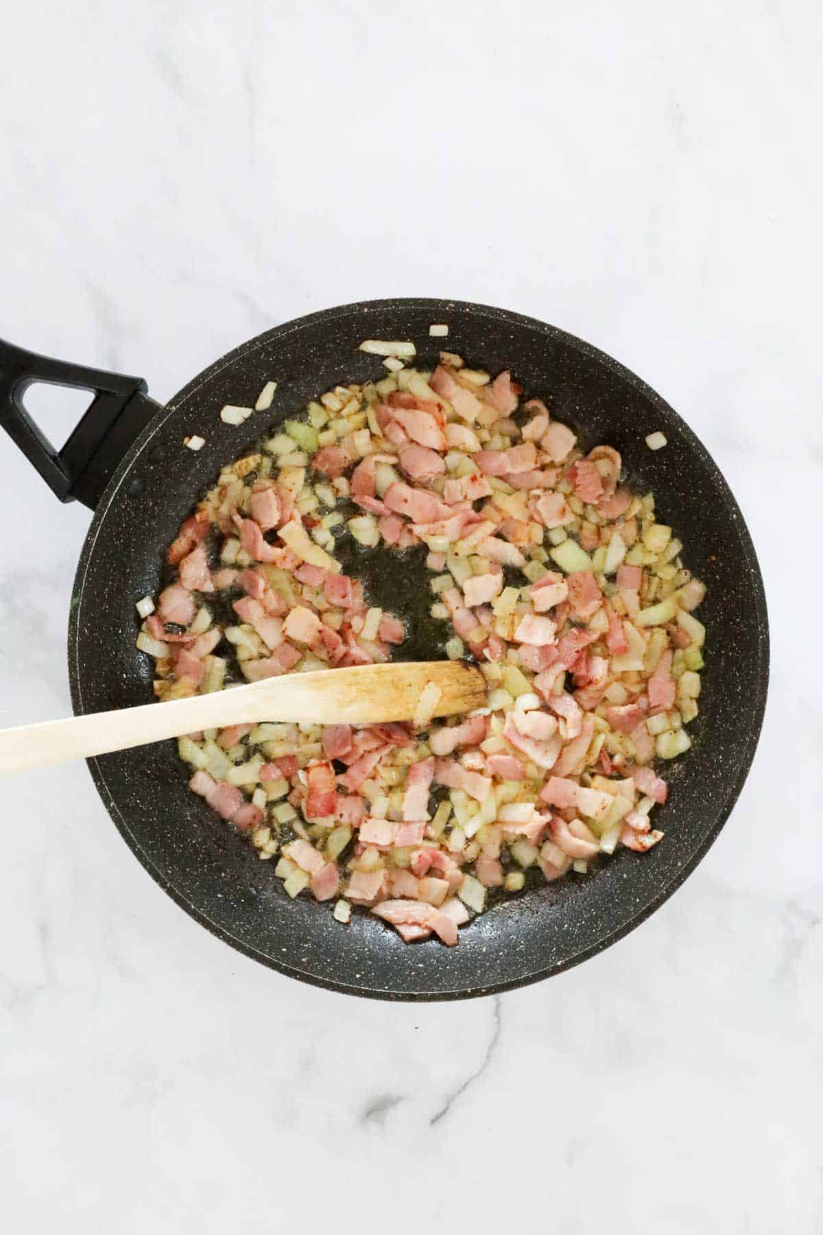 Diced bacon and onion in a large frying pan.