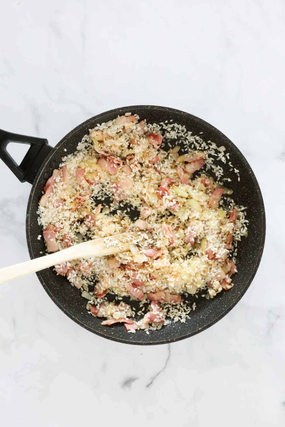 Arborio rice added to the cooked bacon and onion in the frying pan.
