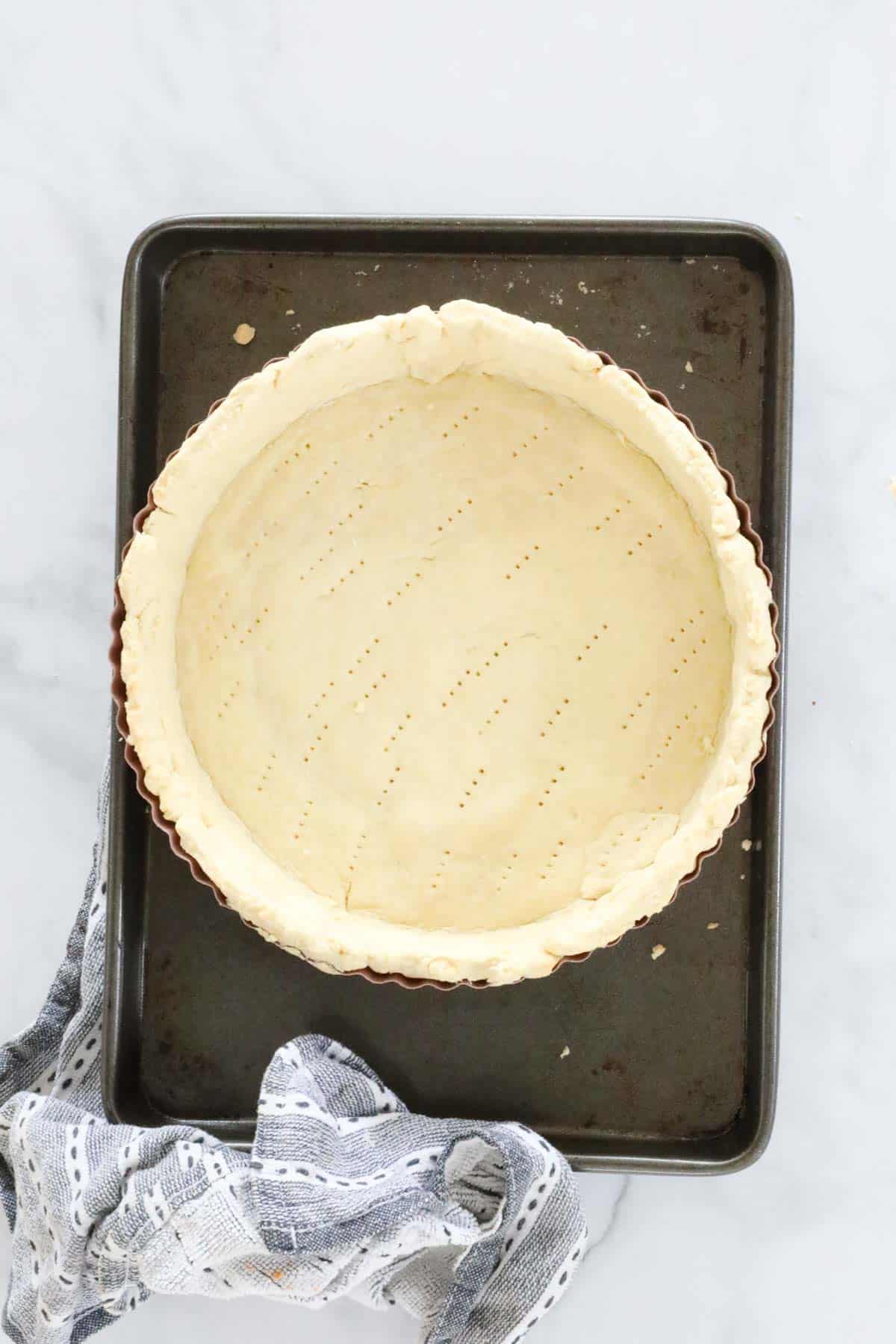 A shortcrust pastry shell on a baking tray.