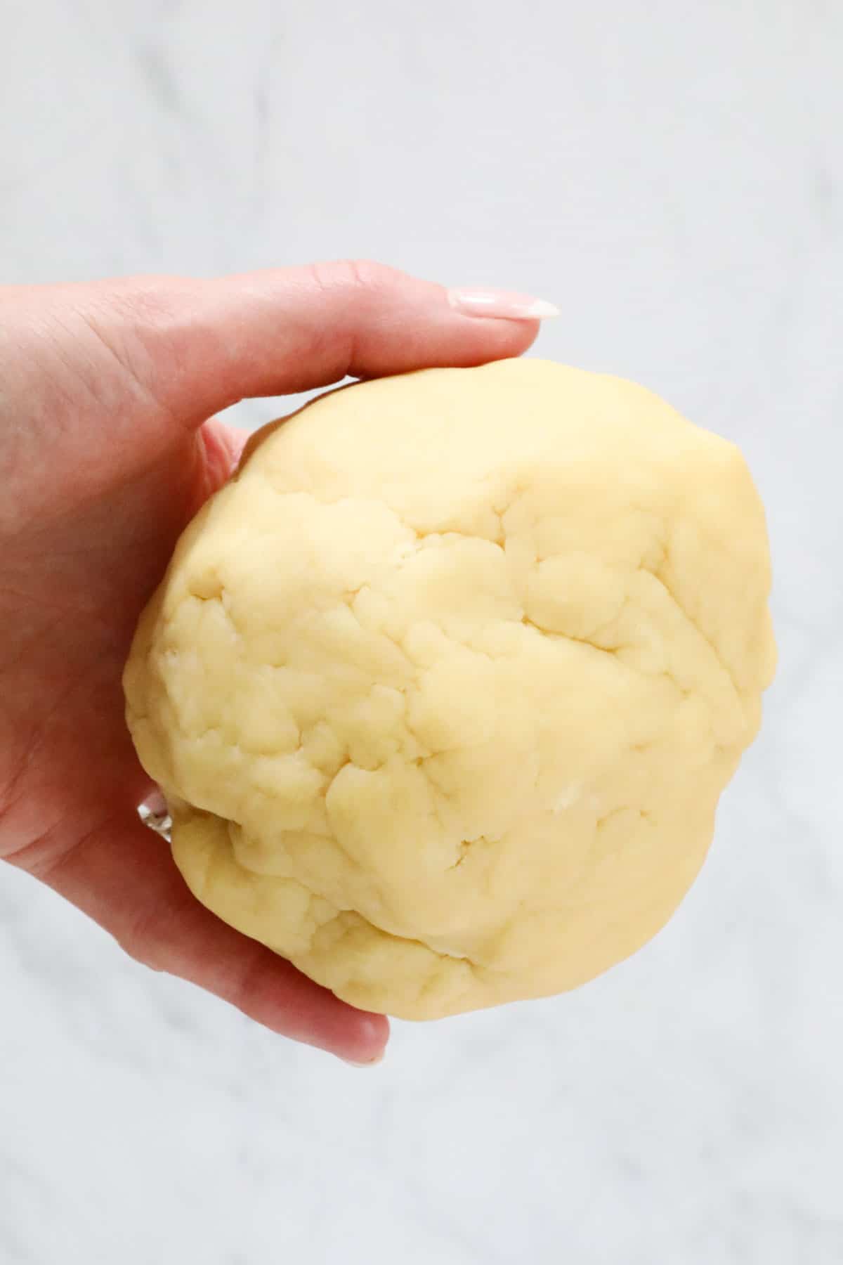 A hand holding a ball of homemade pastry.