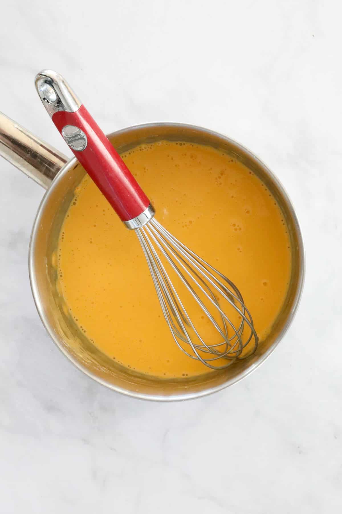 Custard ingredients whisked together in a saucepan.