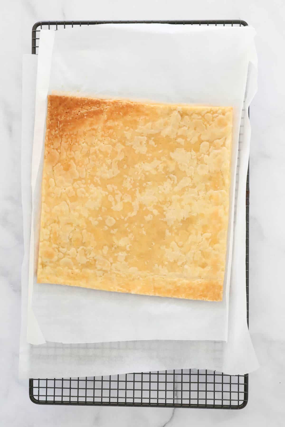A sheet of baked puff pastry on baking paper.