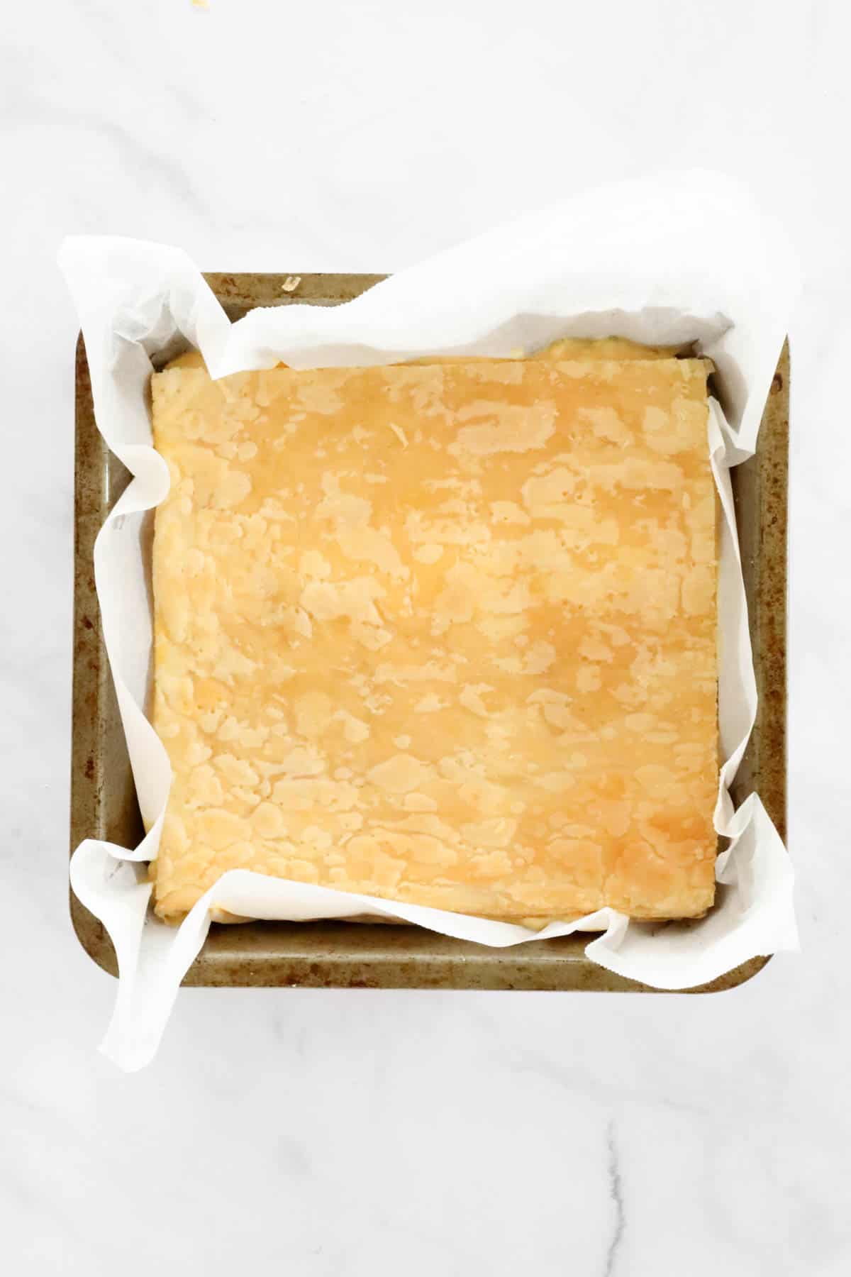 The top layer of puff pastry placed on top of the thickened custard in the baking tin.