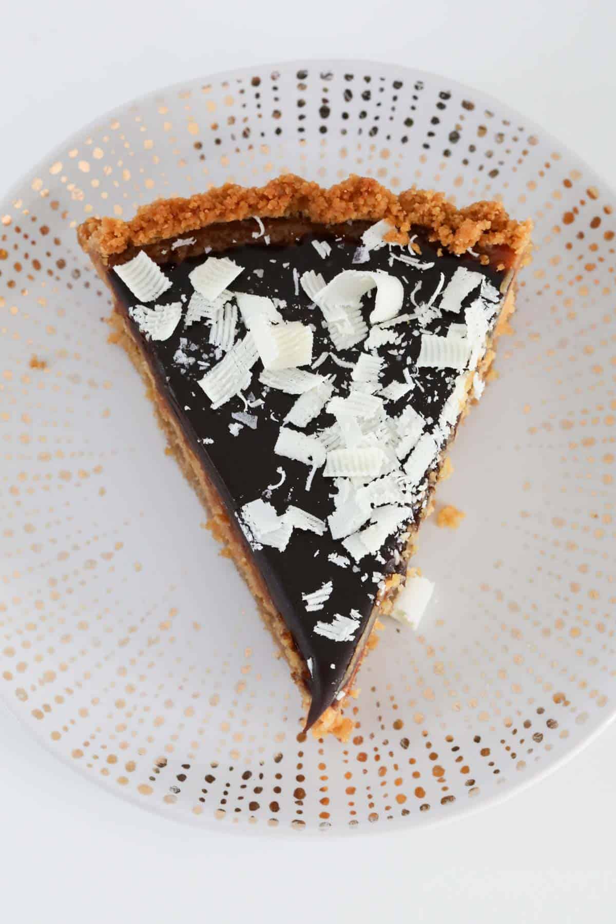 An overhead shot of chocolate caramel tart with grated white chocolate sprinkled over the top.