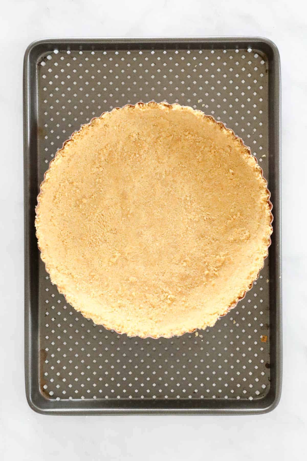 Biscuit crumb base pressed into a tart tin.