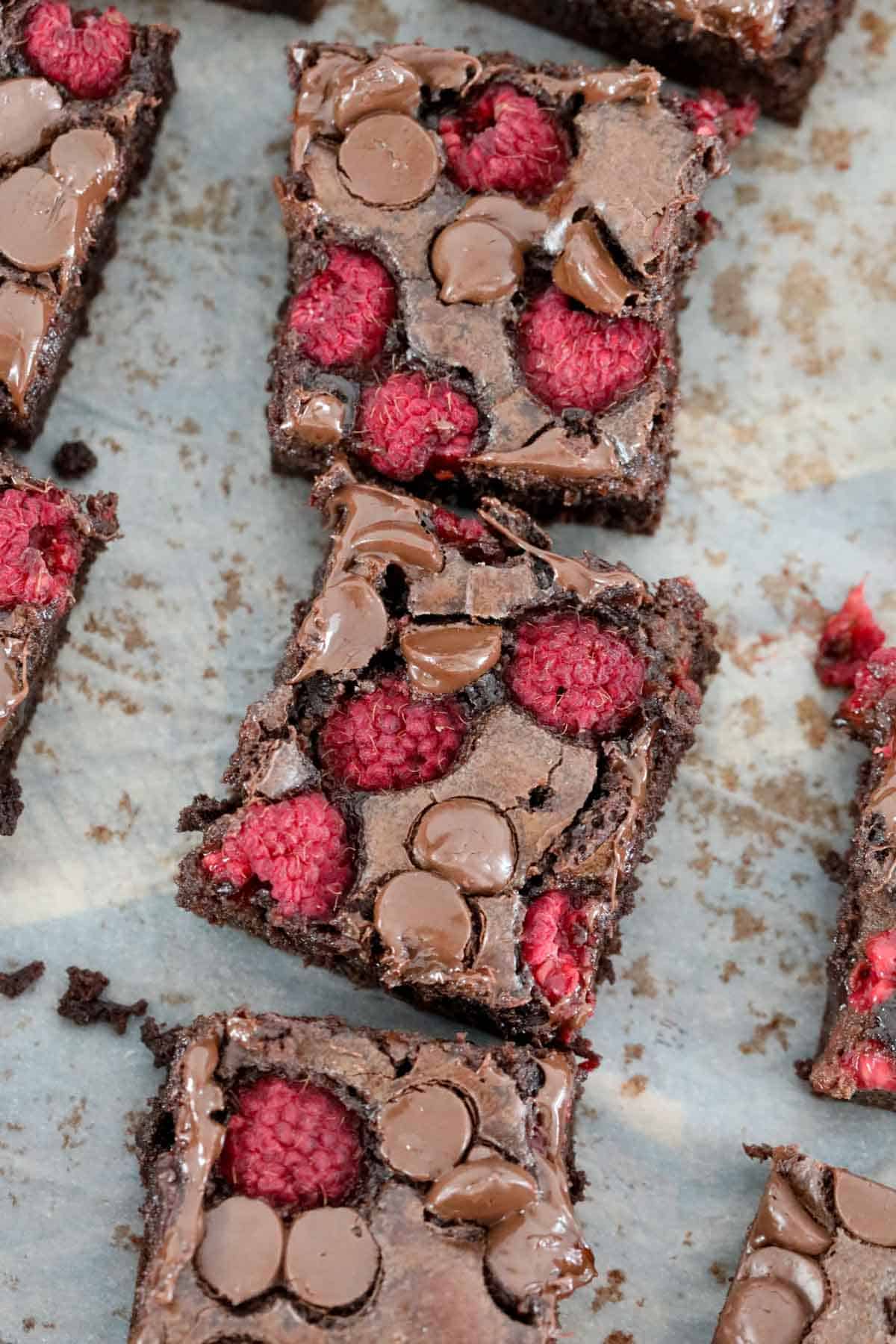 Raspberry brownie squares cut and placed on baking paper.