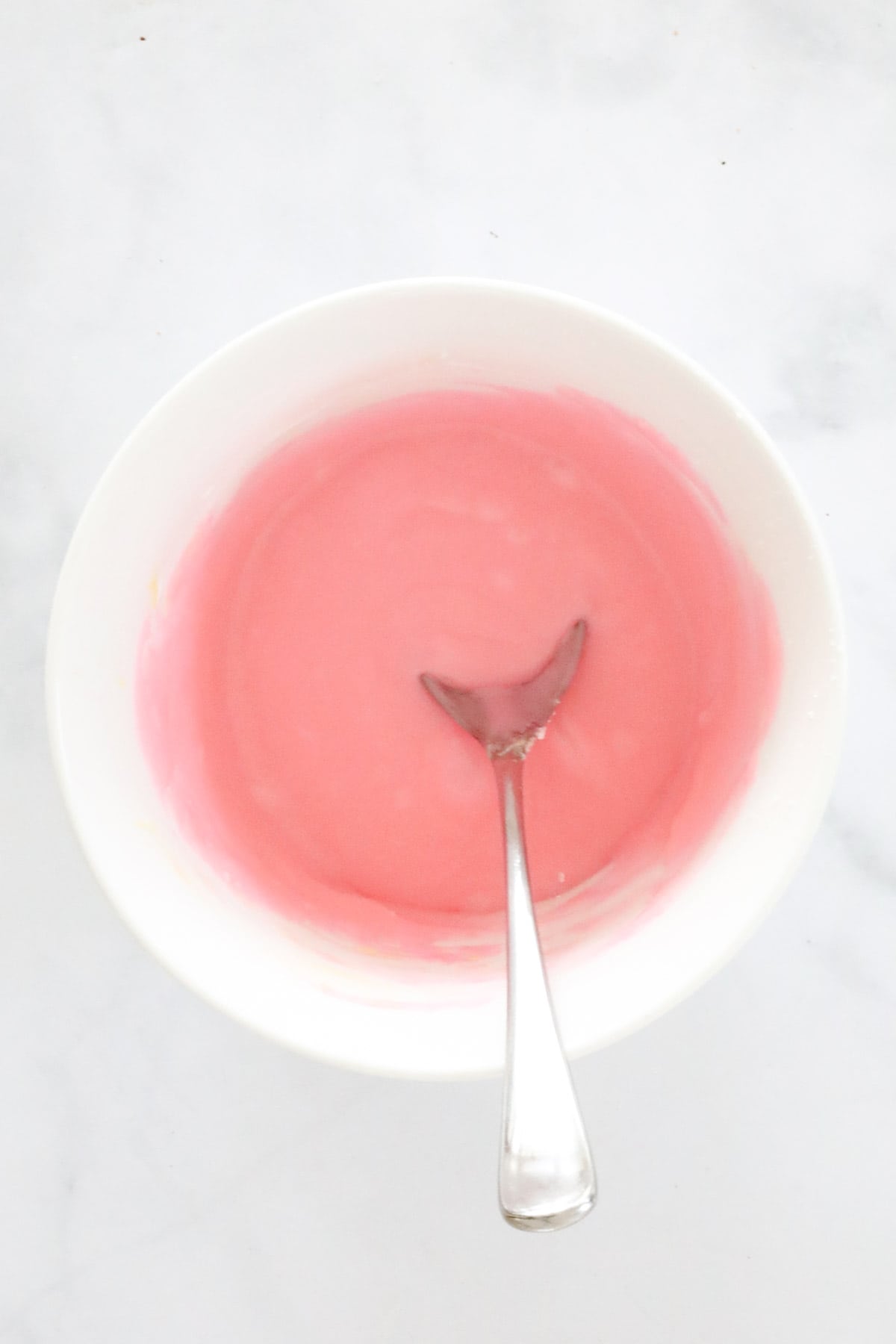 Pink icing mixed together in a bowl.