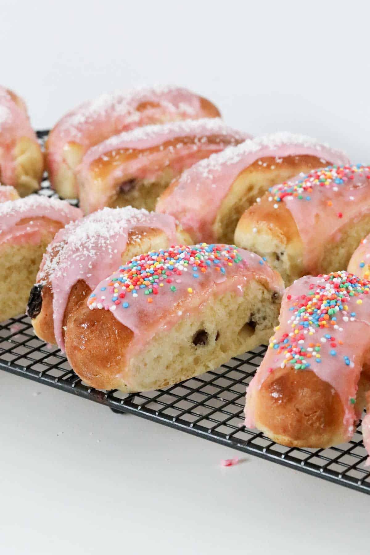 side view of some iced finger buns to show the fruit studded dough.