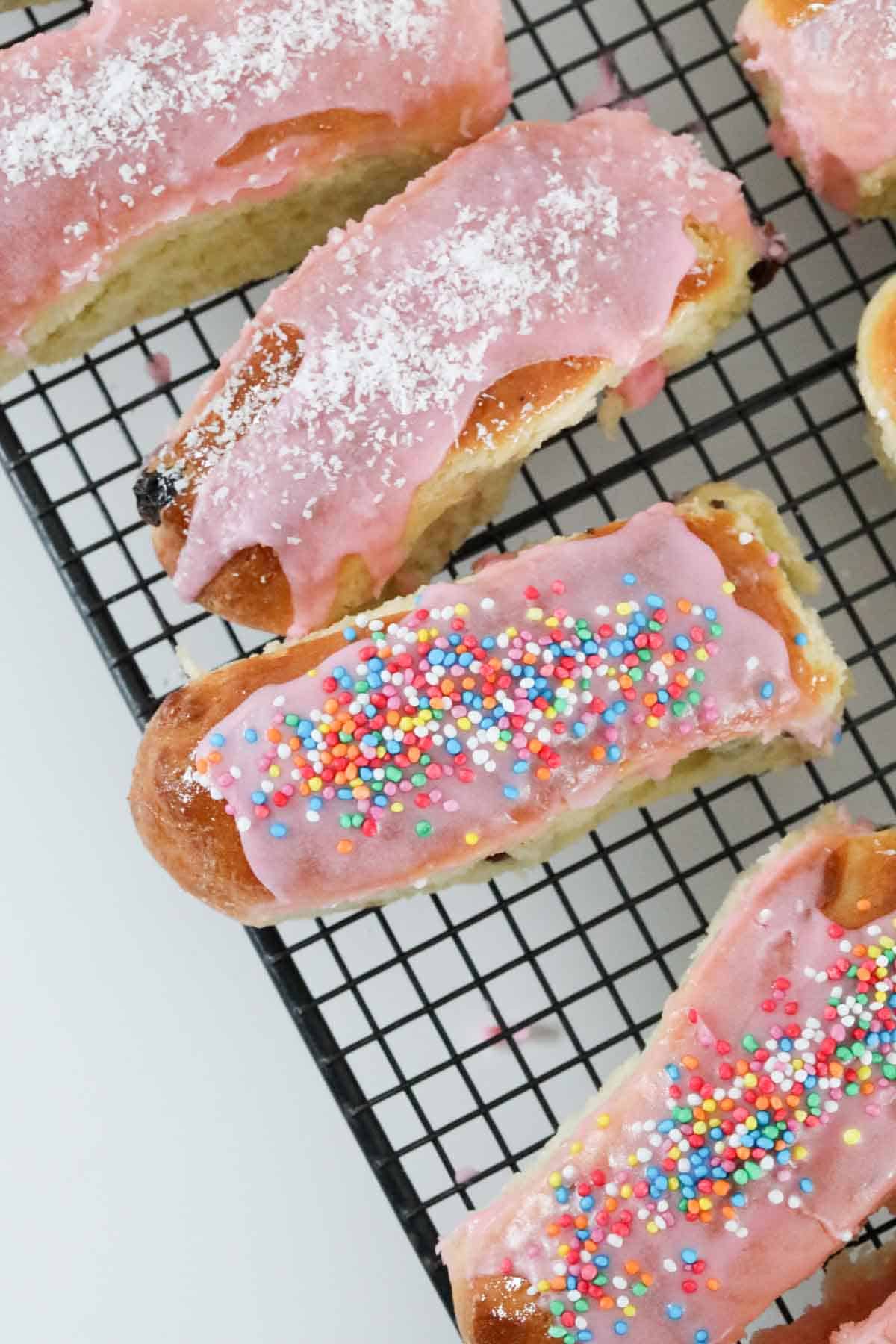Sweet pink iced finger buns on a wire cooling rack.