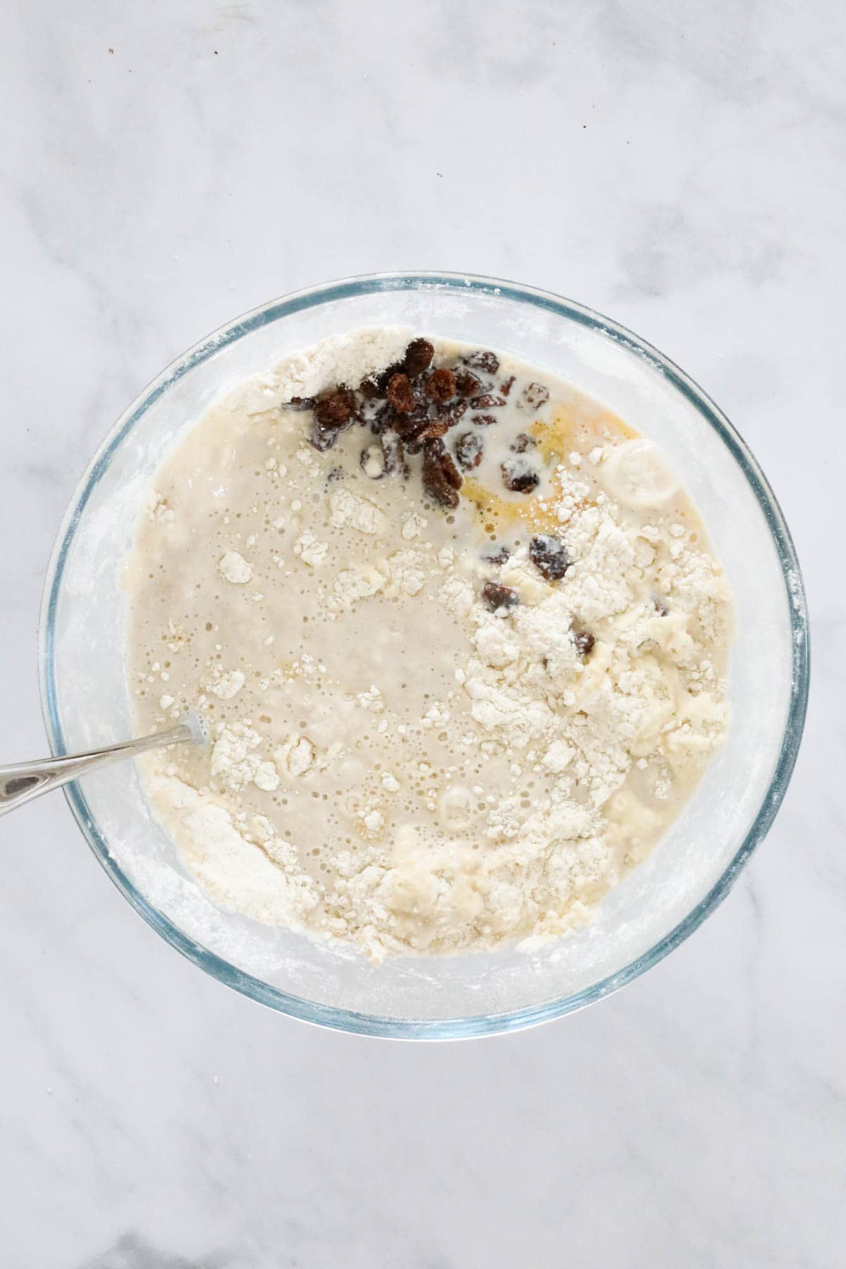 Yeast mixture and sultanas added to the flour in the mixing bowl.