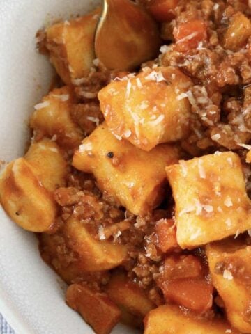 A bowl of homemade ricotta gnocchi with a meat bolognese sauce.