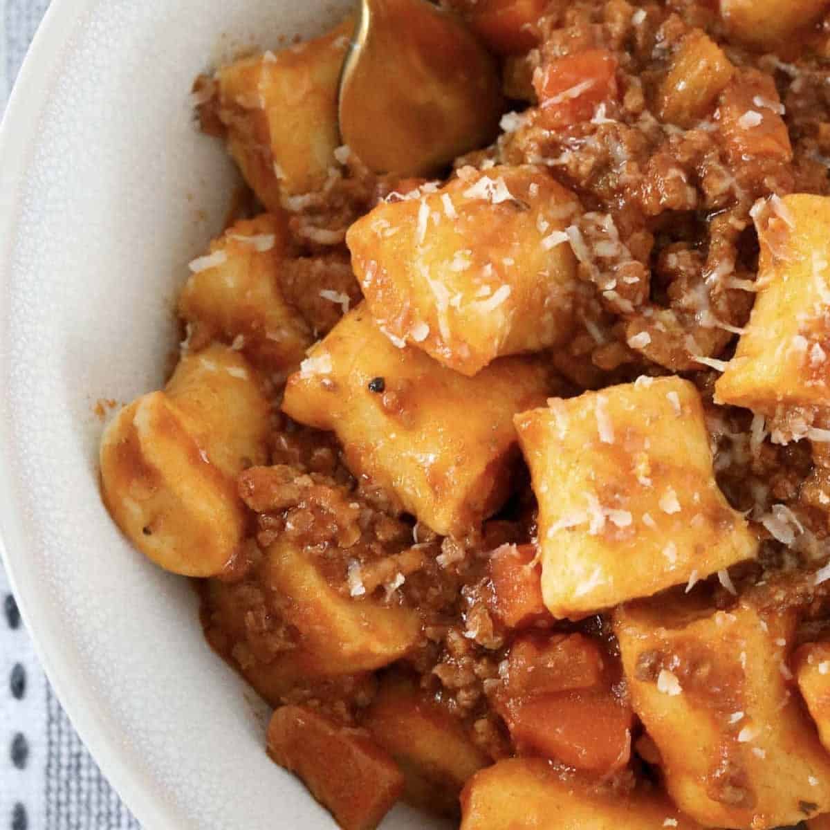 A bowl of homemade ricotta gnocchi with a meat bolognese sauce.