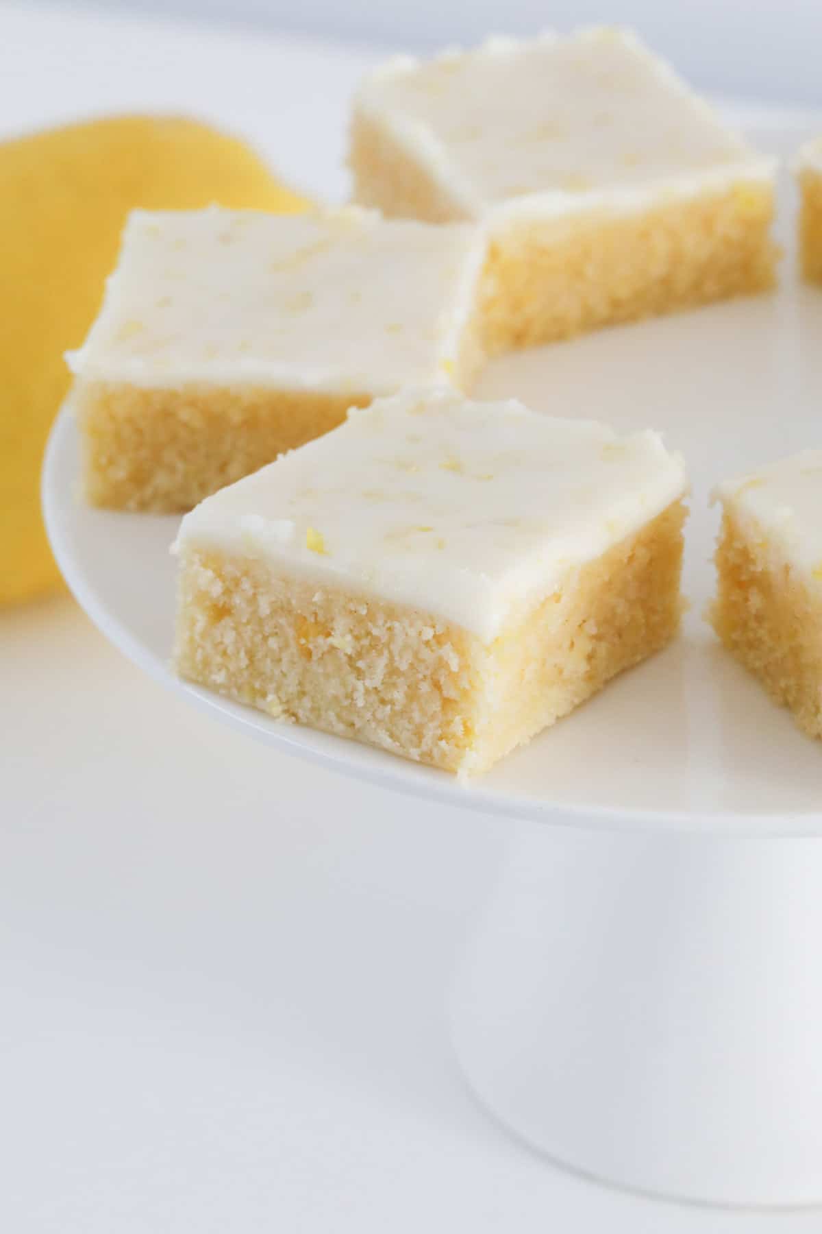 Lemon blondies on a white cake stand.