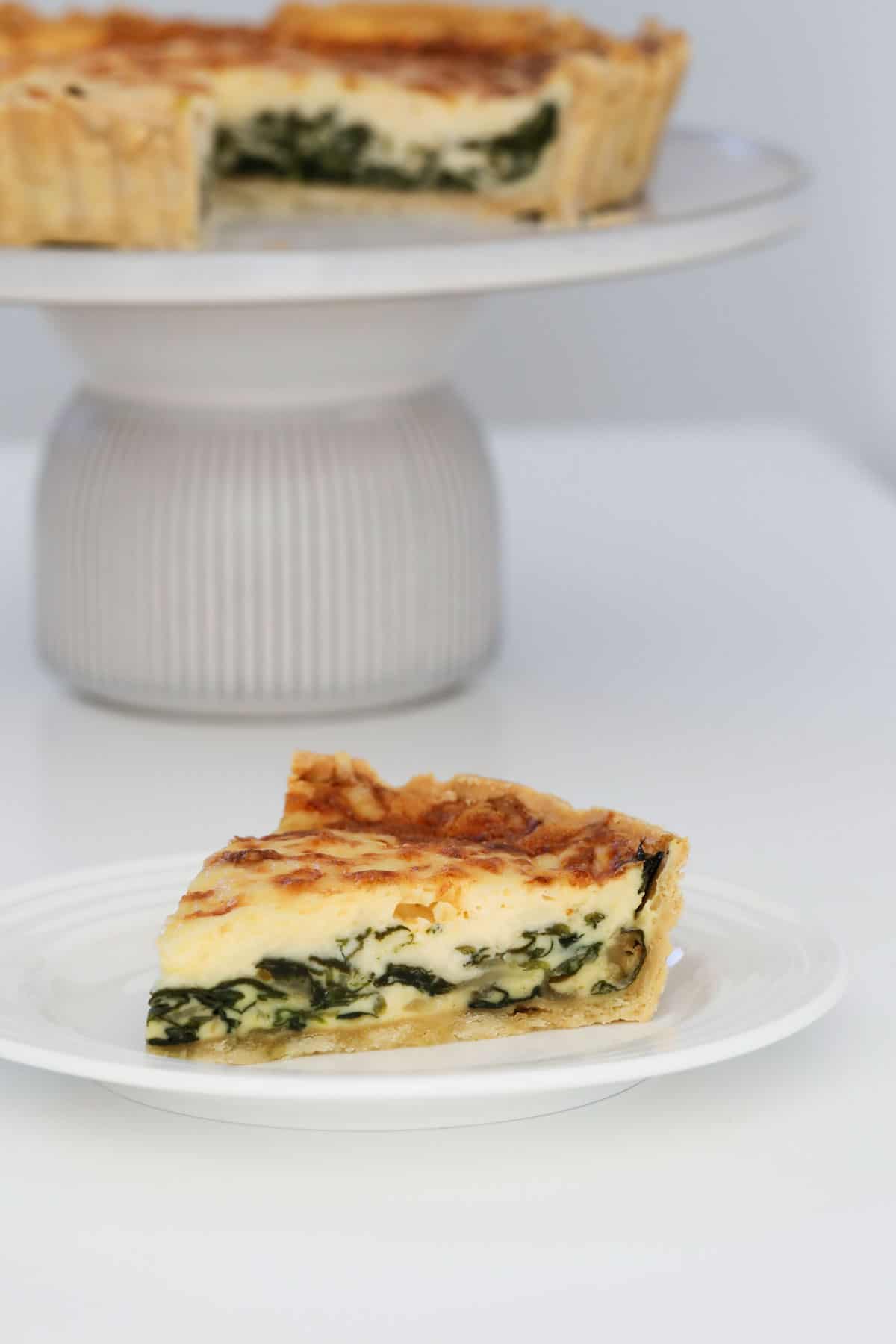 A wedge of florentine quiche served on a plate.