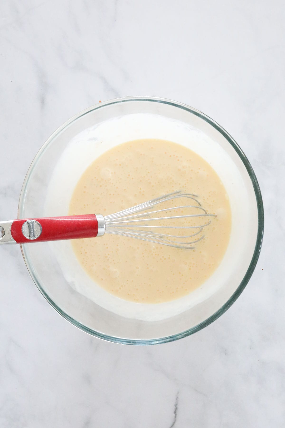Eggs and cream whisked together in a mixing bowl.