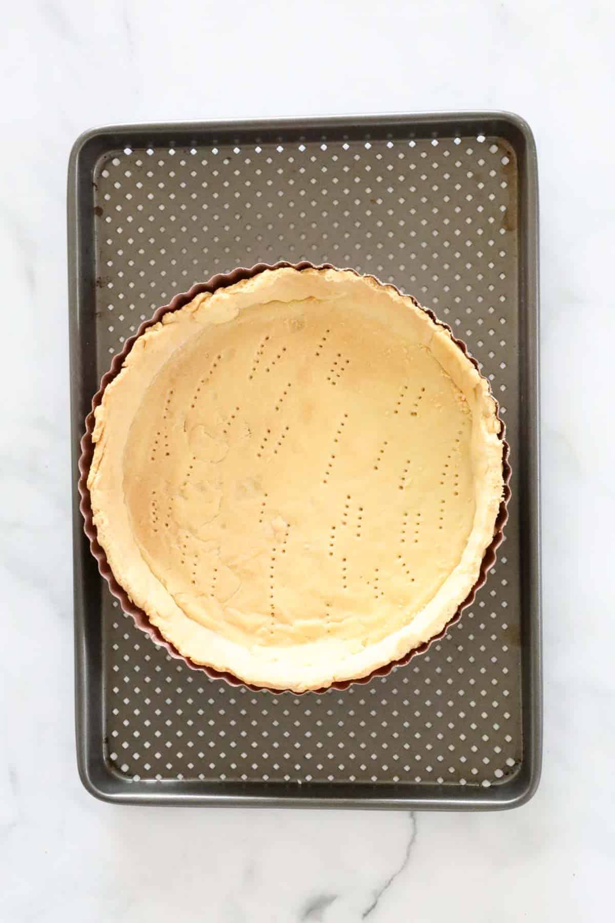 A pastry shell that has been blind baked, in a tart tin.