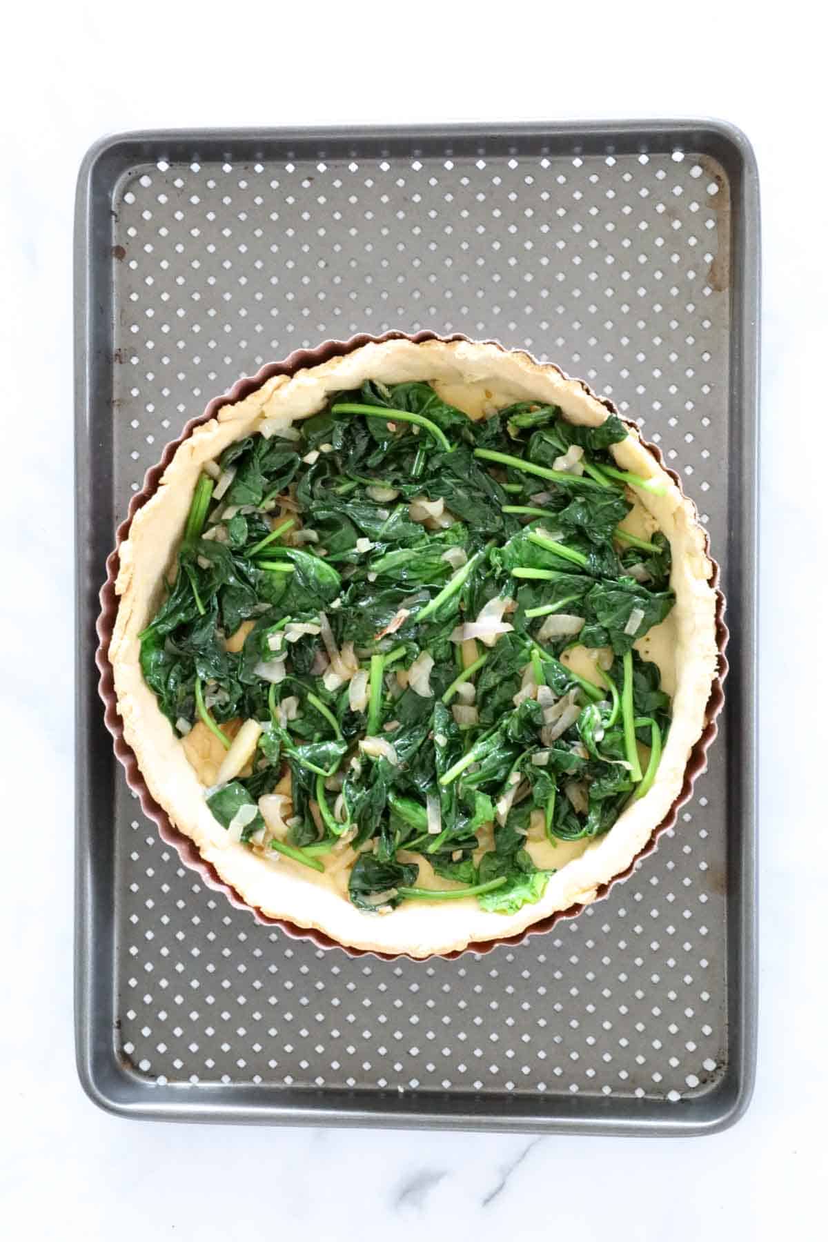 Spinach and shallots spread over baked pastry shell.