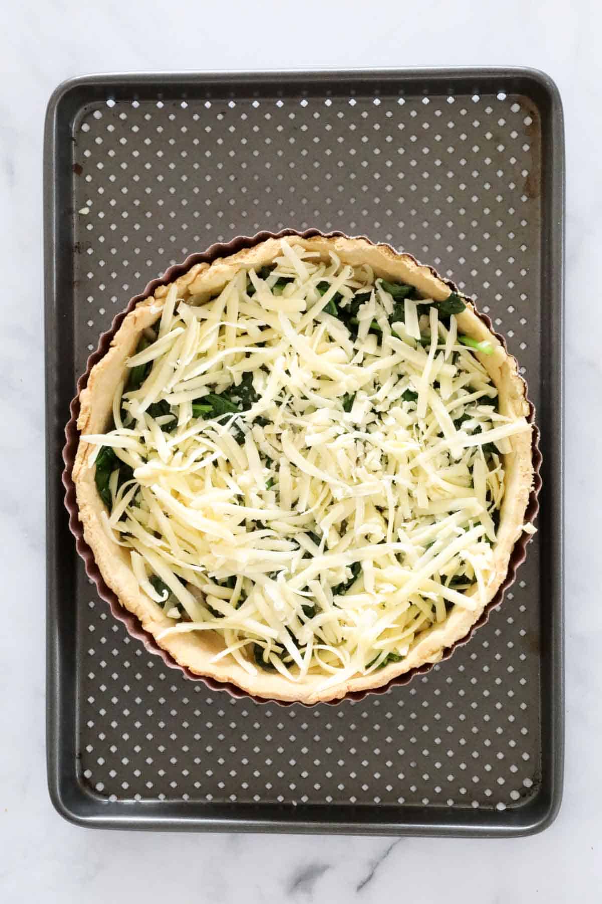 Grated cheese sprinkled over spinach in pastry shell.