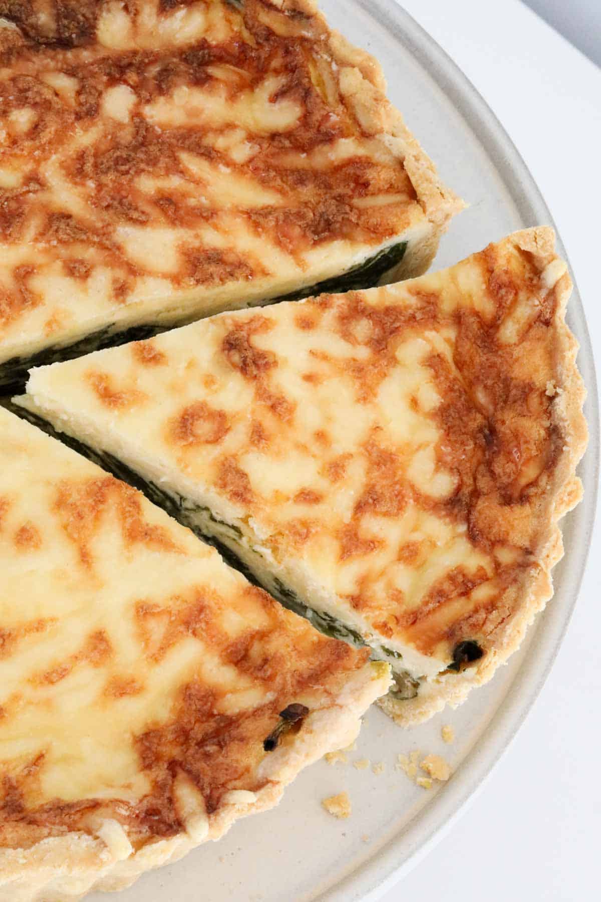 A golden quiche florentine cut, with one serve slightly removed.