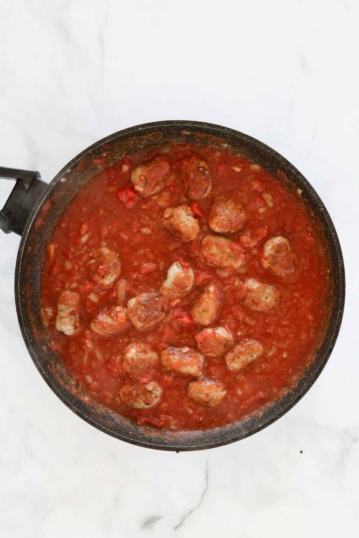 Meatballs returned to the pan filled with tomato sauce.