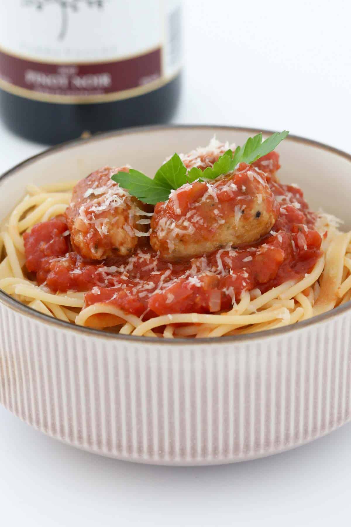 Italian sausage meatballs cooked in tomato based sauce, piled on to a bowl of cooked spaghetti.