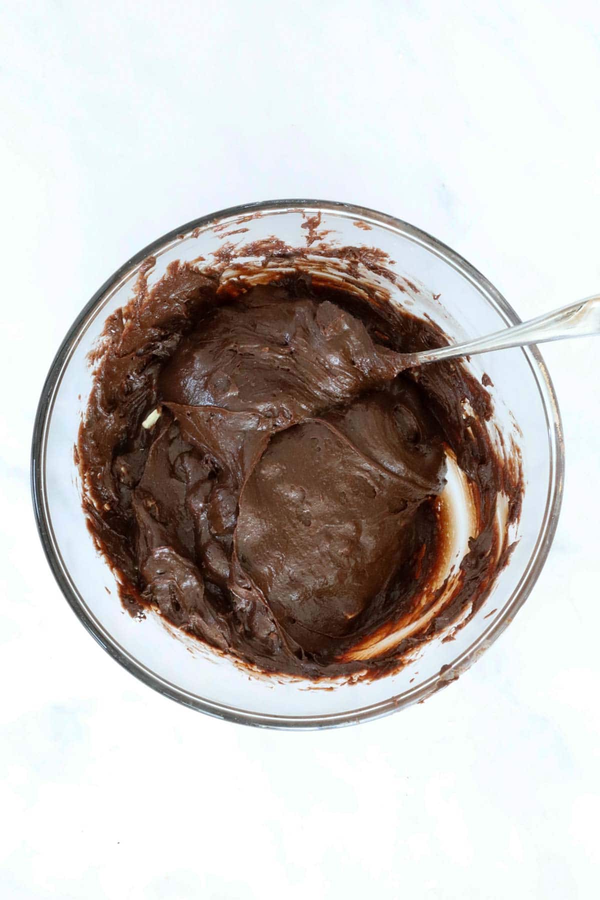 A dark chocolate mxture in a glass mixing bowl.