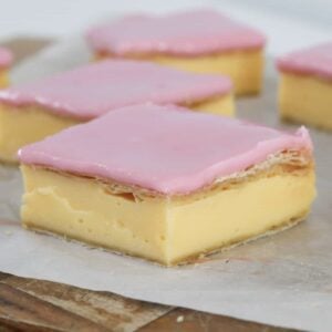 Pieces of homemade vanilla custard slice with pink icing.