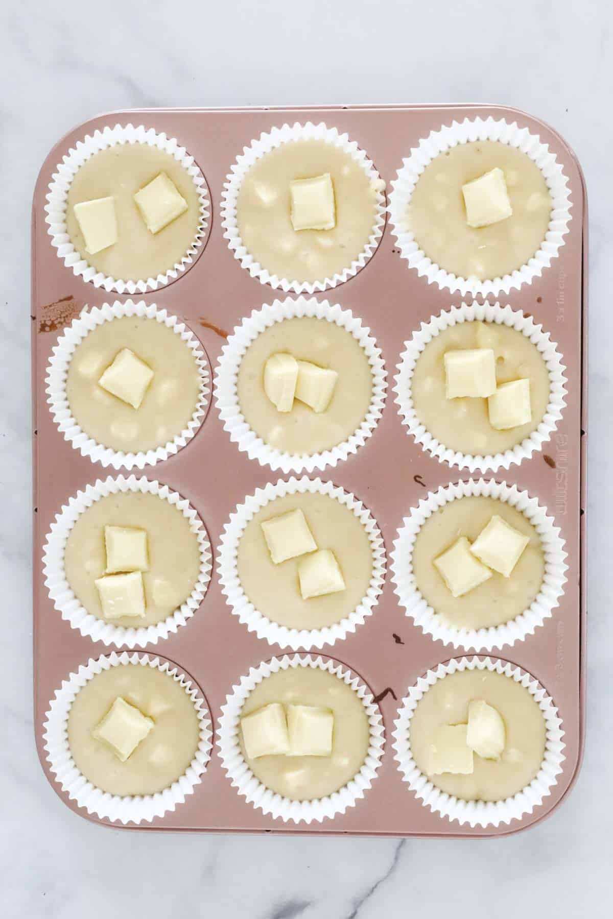 Chunks of white chocolate on top of muffin batter.