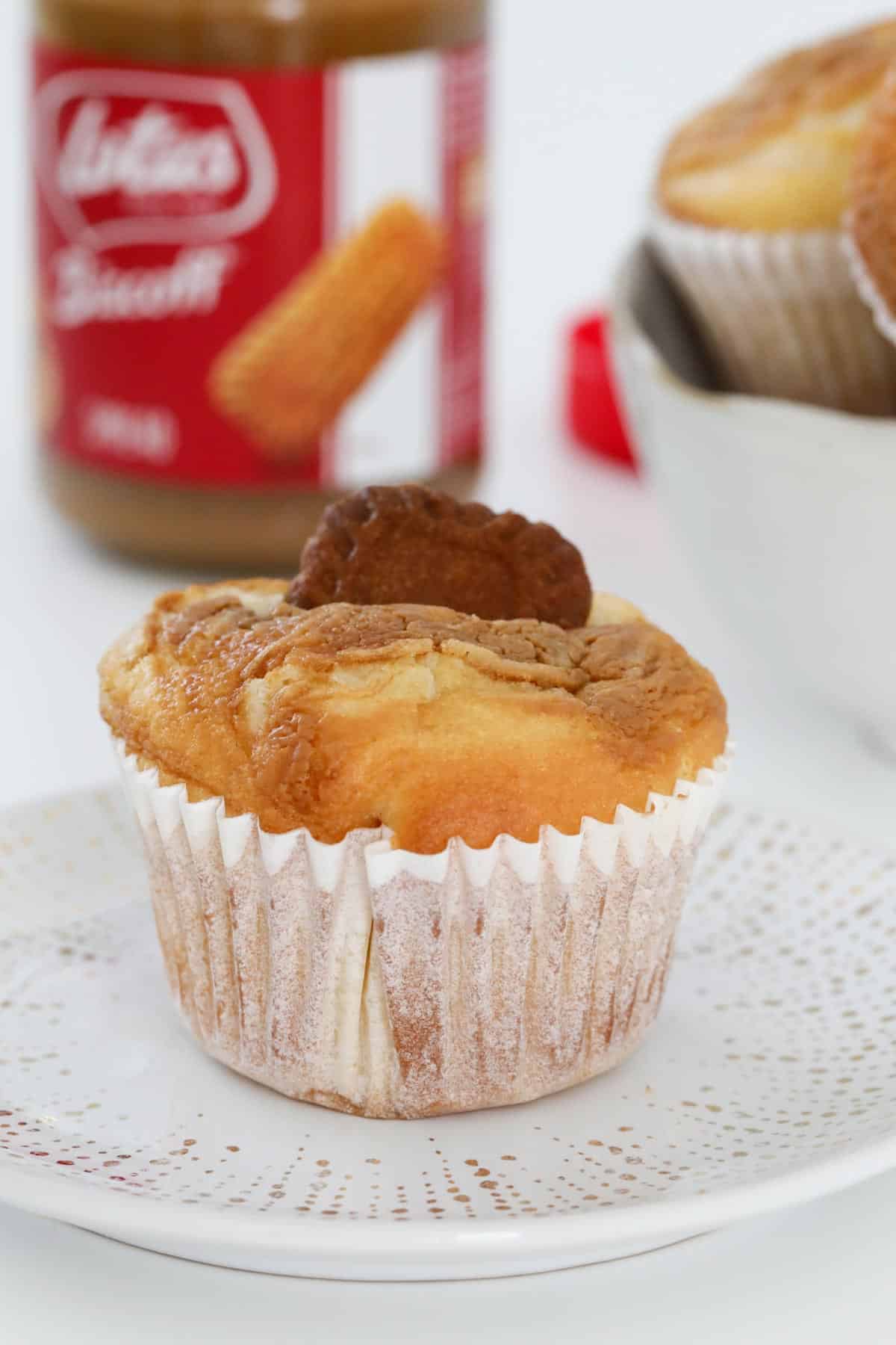A muffin in front of a jar of Biscoff spread.