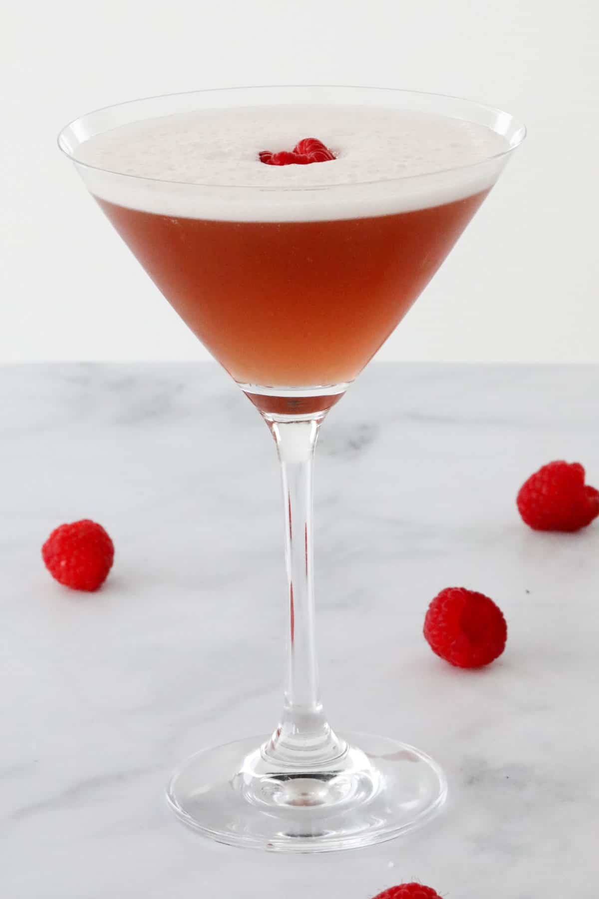 A french cocktail served in a martini glass with raspberries.