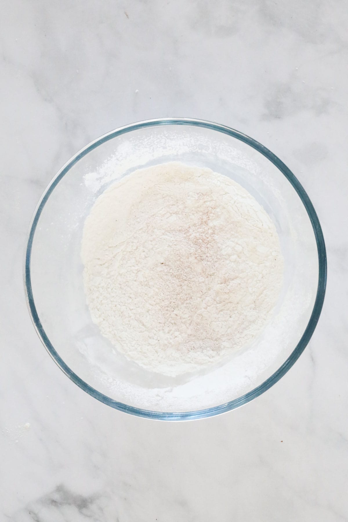 Sifted flour in a clear glass mixing bowl.