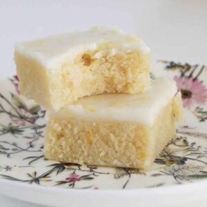 Fudgy lemon blondies stacked on a floral plate.