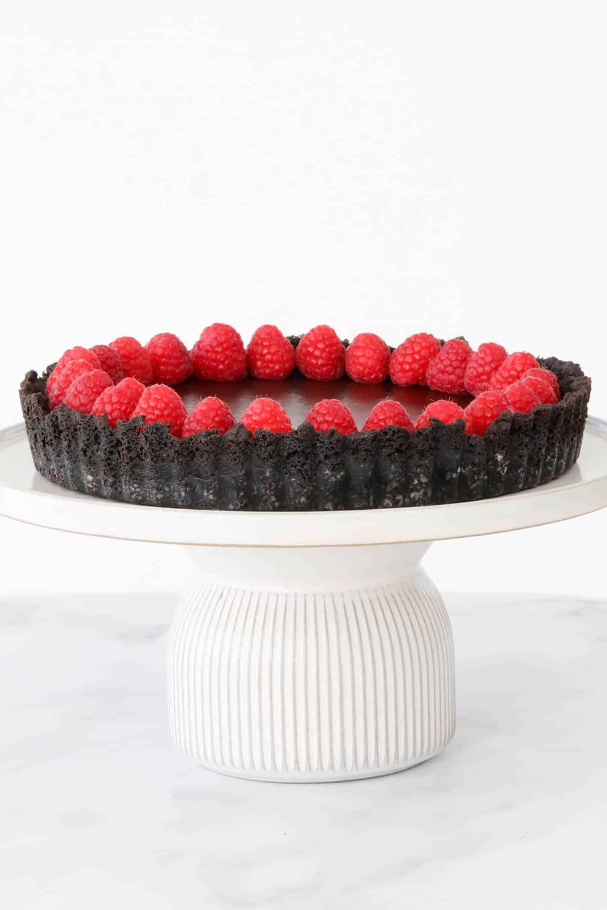 Chocolate ganache and raspberry tart on a cake stand.