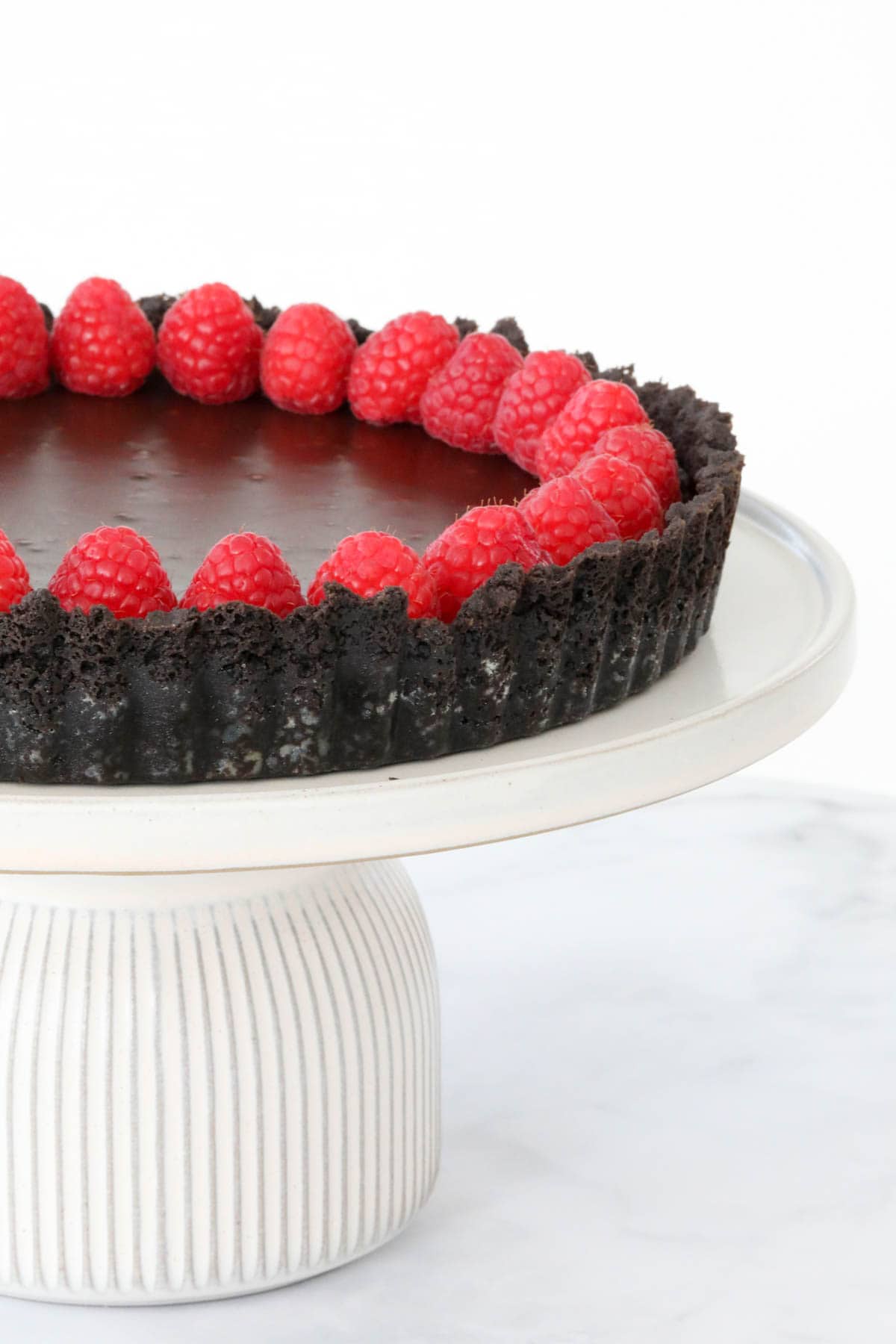 Fresh raspberries decorating the edge of a chocolate tart.