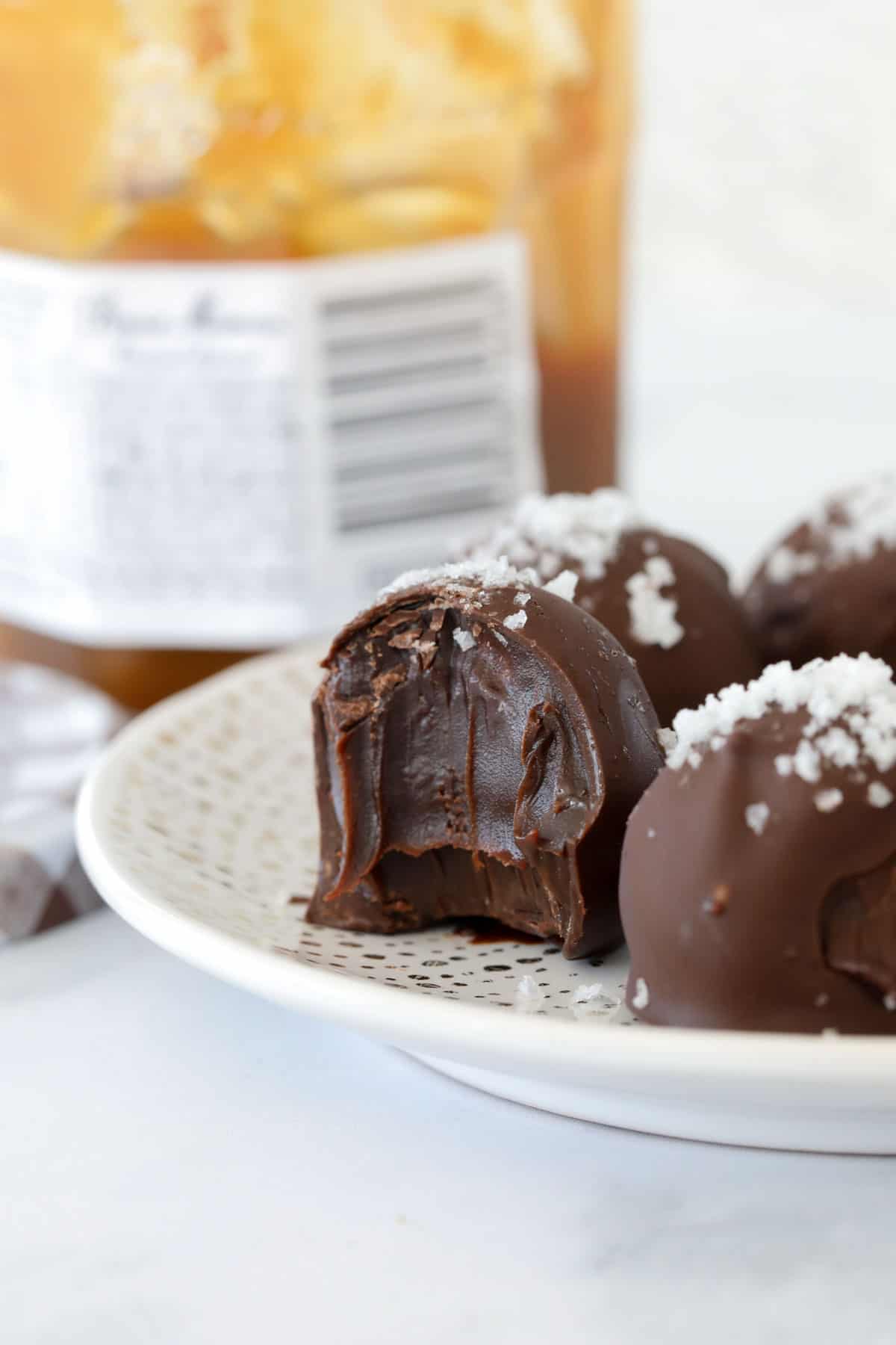 A salted caramel truffle bitten in half to show the smooth ganache filling.