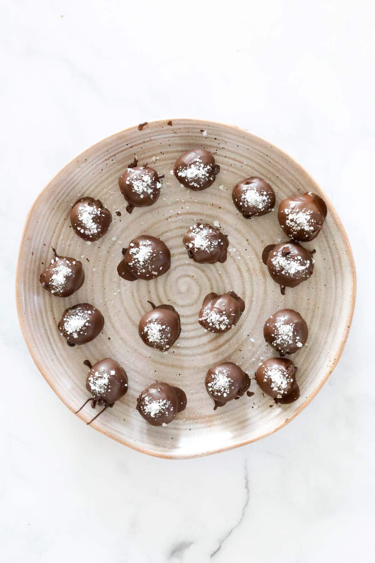 The truffles dipped in chocolate and sprinkled with sea salt on a plate.