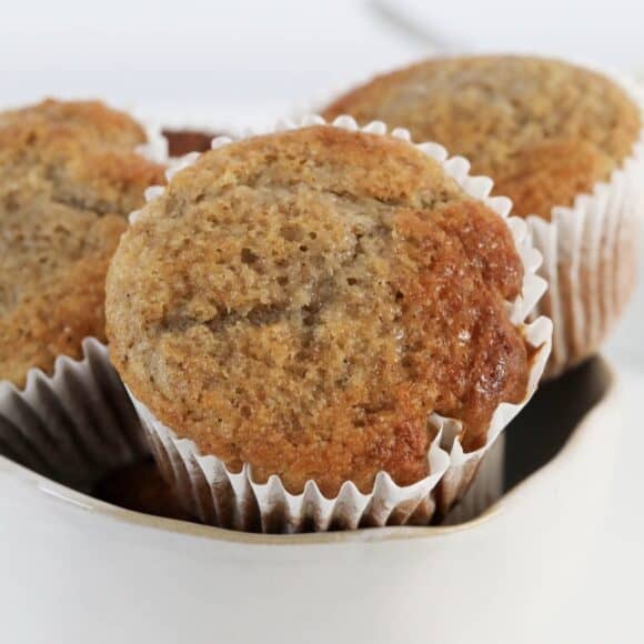 Soft banana muffins with a golden crunchy top on a wire rack.