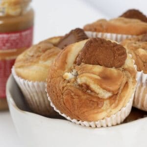 A bowl filled with muffins swirled with Biscoff spread and decorated with a Biscoff cookie.