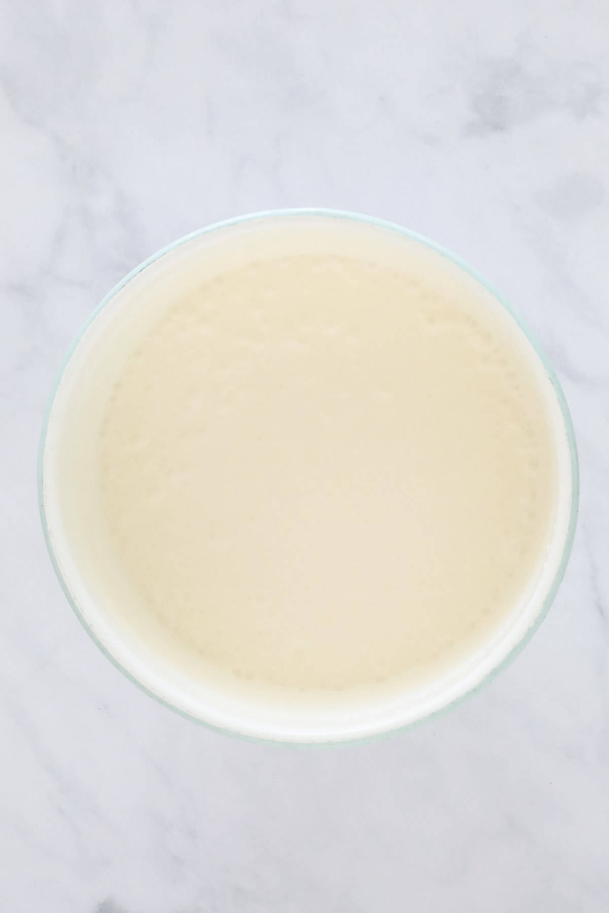Condensed milk and cream beaten together in a white mixing bowl.