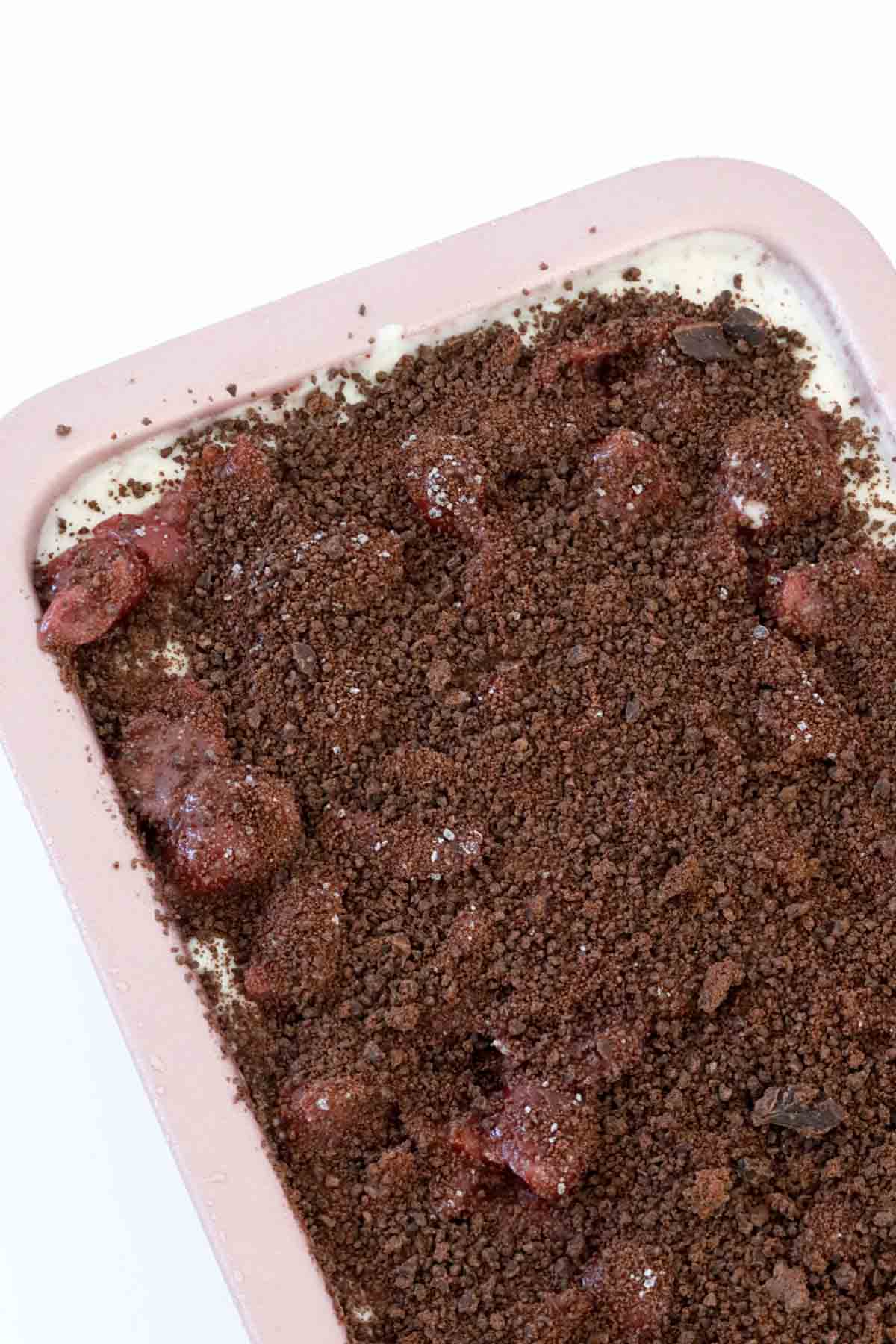 Chunks of cherries and grated dark chocolate spread over a frozen dessert in a loaf tin.